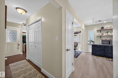 Entryway featuring wood-finish flooring, a bi-fold closet, and a front door with decorative glass - 8310 99 Avenue, Fort Saskatchewan, AB - Indoor Photo Showing Other Room