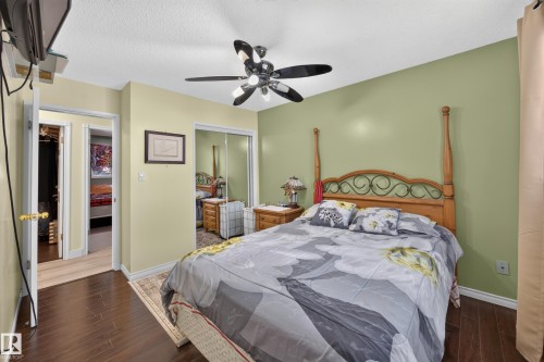 Bedroom featuring dark wood-finish flooring, two-tone wall paint, and a ceiling fan with integrated lighting - 8310 99 Avenue, Fort Saskatchewan, AB - Indoor Photo Showing Bedroom