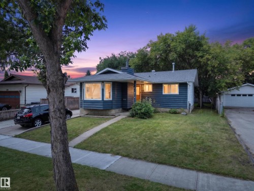 Blue exterior siding with a bay window, a front lawn with a concrete walkway, and an attached garage - 8310 99 Avenue, Fort Saskatchewan, AB - Outdoor With Facade