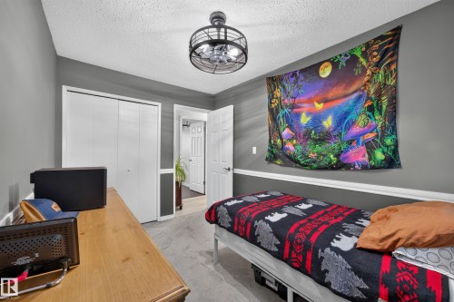Room featuring gray painted walls with white trim, a ceiling fan with a black cage design, light-colored carpet, and bi-fold closet doors - 8310 99 Avenue, Fort Saskatchewan, AB - Indoor Photo Showing Bedroom