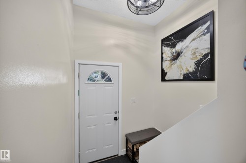 Entryway with a white paneled door featuring an arched decorative glass insert and a black door handle - 8310 99 Avenue, Fort Saskatchewan, AB - Indoor Photo Showing Other Room
