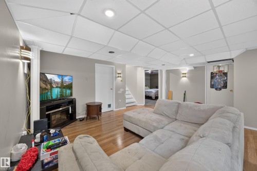 Lower level living space featuring wood-finish flooring, recessed lighting, and wall sconces - 8310 99 Avenue, Fort Saskatchewan, AB - Indoor Photo Showing Living Room