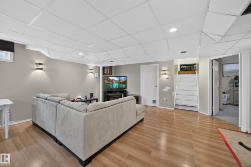 Spacious finished room featuring wood-finish flooring, recessed lighting, and modern wall sconces - 8310 99 Avenue, Fort Saskatchewan, AB - Indoor