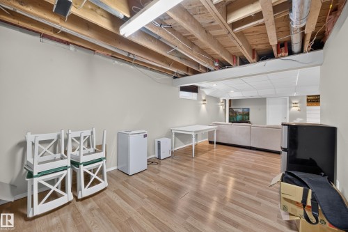 Finished lower level featuring wood-finish flooring, drop ceiling panels, recessed lighting, and wall sconces - 8310 99 Avenue, Fort Saskatchewan, AB - Indoor Photo Showing Basement
