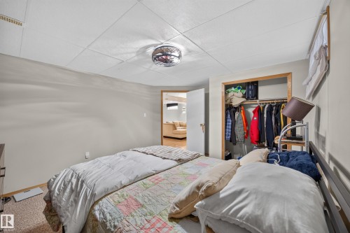Bedroom featuring neutral wall paint, carpet flooring, a drop ceiling, and an open closet with built-in shelving - 8310 99 Avenue, Fort Saskatchewan, AB - Indoor Photo Showing Bedroom