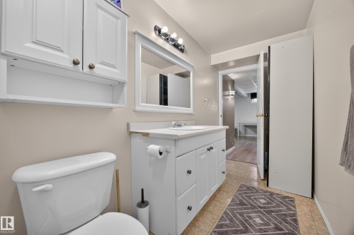 Bathroom featuring a white vanity with integrated sink, coordinating wall cabinet, framed mirror, and tile-finish flooring - 8310 99 Avenue, Fort Saskatchewan, AB - Indoor Photo Showing Bathroom