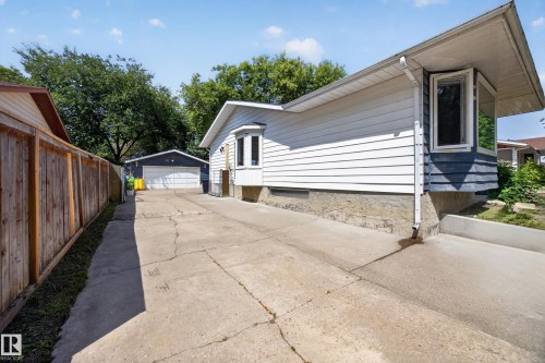 Long concrete driveway providing access to a detached garage - 8310 99 Avenue, Fort Saskatchewan, AB - Outdoor With Exterior