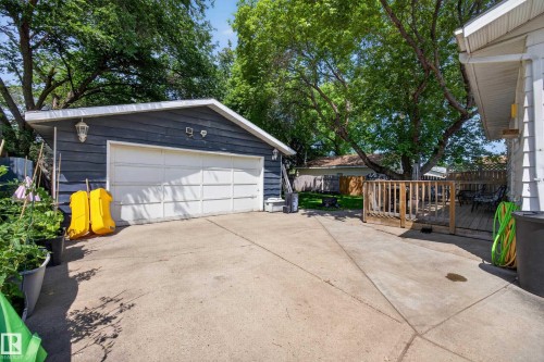 Detached garage with horizontal siding, concrete driveway, and an adjacent wood deck with railing - 8310 99 Avenue, Fort Saskatchewan, AB - Outdoor With Exterior