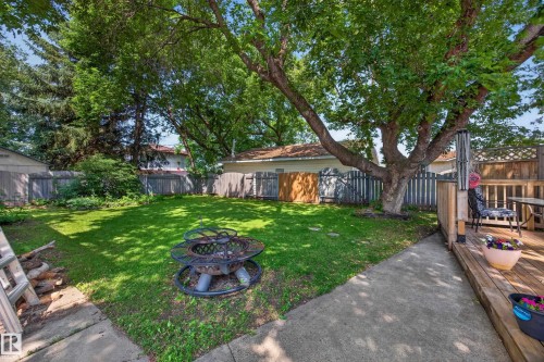 Spacious backyard featuring a substantial lawn area, concrete patio, and a wooden deck - 8310 99 Avenue, Fort Saskatchewan, AB - Outdoor With Backyard