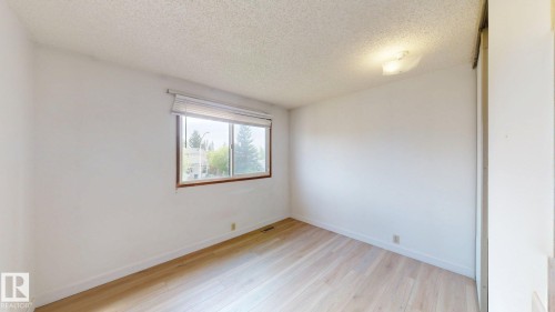 Bright interior space featuring light wood-finish flooring and a large window with horizontal blinds - 4912 34A Avenue, Edmonton, AB - Indoor Photo Showing Other Room