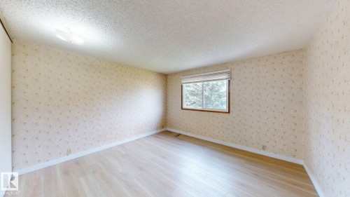 Room featuring light wood-finish flooring, patterned wallpaper, and a single window with a blind - 4912 34A Avenue, Edmonton, AB - Indoor Photo Showing Other Room
