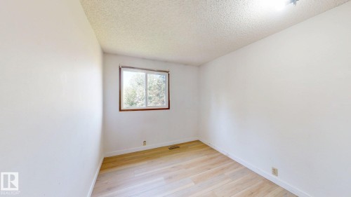 Room featuring wood-finish flooring, white walls, and a window with wood trim - 4912 34A Avenue, Edmonton, AB - Indoor Photo Showing Other Room