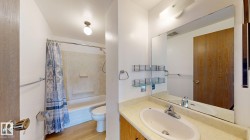 Bathroom featuring a single vanity with an integrated sink, a large mirror, a combined shower and tub, and wood-finish flooring - 