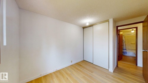 Light wood-finish flooring with white baseboards and neutral wall tones - 4912 34A Avenue, Edmonton, AB - Indoor Photo Showing Other Room