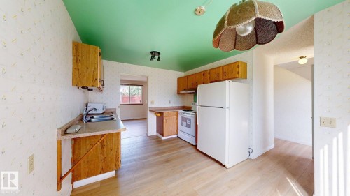 Kitchen featuring light wood-finish flooring, wood cabinetry, and a double basin sink - 4912 34A Avenue, Edmonton, AB - Indoor Photo Showing Kitchen With Double Sink
