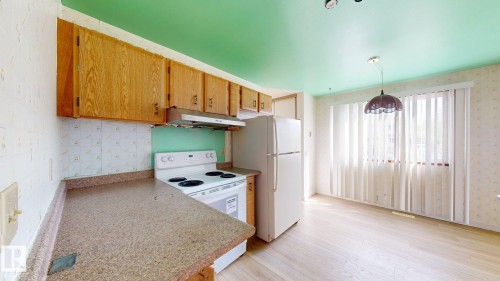 Kitchen space featuring wood cabinetry, white appliances, speckled countertops, and a full-size window with vertical blinds - 4912 34A Avenue, Edmonton, AB - Indoor Photo Showing Kitchen