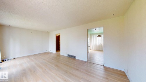 Spacious room with light wood-finish flooring, neutral walls, and textured ceiling - 4912 34A Avenue, Edmonton, AB - Indoor Photo Showing Other Room