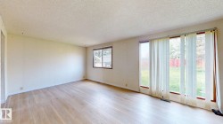 Spacious interior room featuring wood-finish flooring, light-toned walls, and a textured ceiling - 