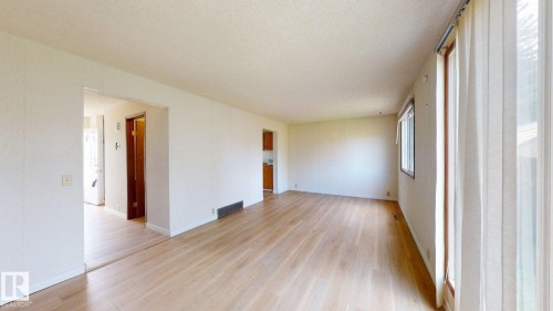 Spacious interior room featuring light wood-finish flooring, white walls, and multiple windows with natural wood frames - 4912 34A Avenue, Edmonton, AB - Indoor Photo Showing Other Room