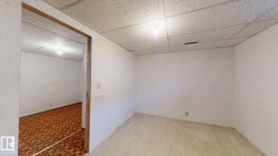 Spacious interior room with light-colored walls, a drop ceiling, and overhead lighting - 