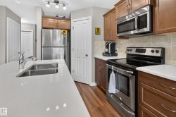 Kitchen featuring a stainless steel undermount sink, white countertops, wood-finish flooring, and matching wood cabinetry - 