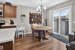 Open-concept kitchen and dining area featuring wood-finish flooring, warm wood cabinetry, and a tile backsplash - 