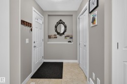 Foyer featuring a paneled entry door with frosted glass accents, light gray wall paint, and tile flooring - 