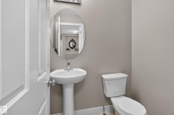 Pedestal sink with chrome faucet, oval mirror, and white toilet - 