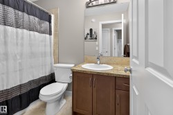 Bathroom featuring a white toilet, tiled flooring, and a shower with tiled surround - 