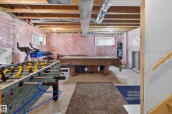 Unfinished basement space featuring exposed wood joists, partial insulation, and concrete flooring - 