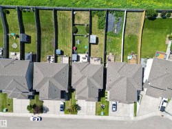 Aerial perspective of multiple properties featuring asphalt shingle roofs and concrete driveways - 