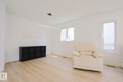 Spacious room featuring light wood-finish flooring, white painted walls, and multiple windows - 