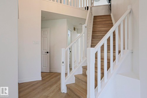L-shaped staircase with light wood-finish treads and white balusters - 11347 10 Avenue, Edmonton, AB - Indoor Photo Showing Other Room
