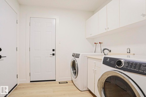 Laundry area featuring overhead cabinetry, a countertop, and light wood-finish flooring - 11347 10 Avenue, Edmonton, AB - Indoor Photo Showing Laundry Room