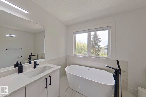 Freestanding soaking tub with a floor-mounted matte black faucet - 11347 10 Avenue, Edmonton, AB - Indoor