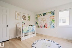 Bright room featuring light wood-finish flooring, white painted walls, a white paneled door with black hardware, and a large window - 