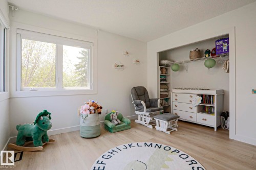 Bright room featuring two windows with white trim, wood-finish flooring, a built-in closet with shelving, and white walls - 11347 10 Avenue, Edmonton, AB - Indoor Photo Showing Bedroom