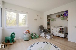 Bright room featuring two windows with white trim, wood-finish flooring, a built-in closet with shelving, and white walls - 