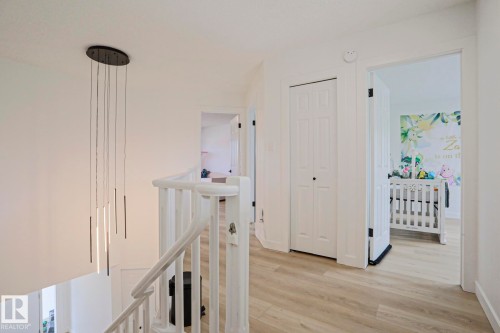 Upper level landing with wood-finish flooring, a contemporary pendant light fixture, and white painted walls - 11347 10 Avenue, Edmonton, AB - Indoor Photo Showing Bathroom