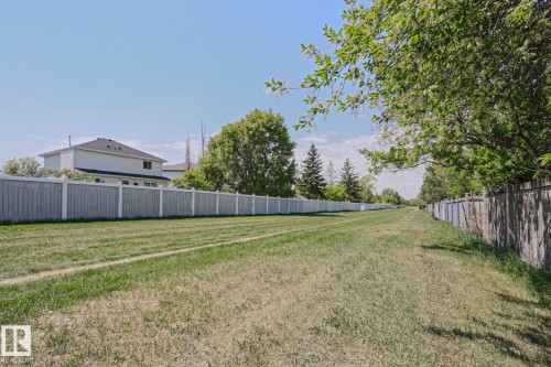 Expansive green space featuring a long stretch of manicured lawn, a light-colored wooden fence, and mature trees providing natural shading - 11347 10 Avenue, Edmonton, AB - Outdoor