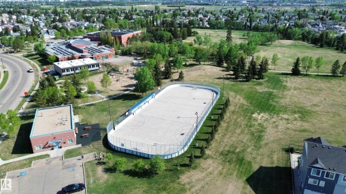 Recreational outdoor rink with perimeter fencing and lighting, bordered by green spaces and mature trees - 11347 10 Avenue, Edmonton, AB - Outdoor With View
