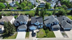 Two-story residence with a light-colored exterior and dark shingle roofing - 