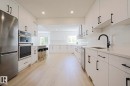 Contemporary kitchen featuring extensive white cabinetry, light wood-finish flooring, recessed lighting, stainless steel appliances, and a matte black faucet - 11347 10 Avenue, Edmonton, AB  - Indoor Photo Showing Kitchen With Upgraded Kitchen 