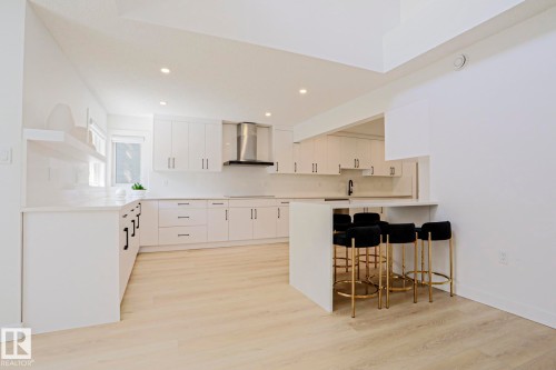 Modern kitchen featuring light wood-finish flooring and a breakfast bar with seating - 11347 10 Avenue, Edmonton, AB - Indoor Photo Showing Kitchen