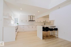 Modern kitchen featuring light wood-finish flooring and a breakfast bar with seating - 