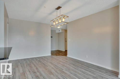Dining area featuring wood-finish flooring, a contemporary linear chandelier - #201 534 Watt Bv Sw, Edmonton, AB - Indoor Photo Showing Other Room