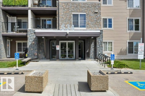 Building facade featuring stone and siding finishes - #201 534 Watt Bv Sw, Edmonton, AB - Outdoor With Facade