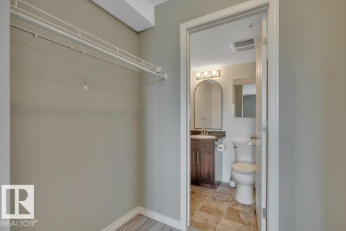 Walk-through closet with to the ensuite with a large walk-in shower. - #201 534 Watt Bv Sw, Edmonton, AB - Indoor Photo Showing Bathroom
