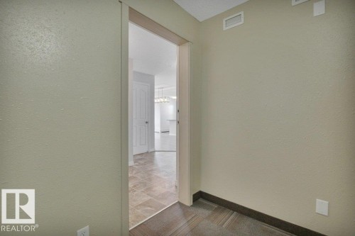 Entryway featuring light-toned textured walls, a dark baseboard, and a patterned tile floor - #201 534 Watt Bv Sw, Edmonton, AB - Indoor Photo Showing Other Room
