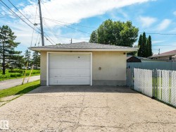 Detached garage featuring a white overhead door and shingle roof - 